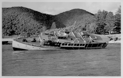 A large boat on it's side in water, shipwrecked on the rocks