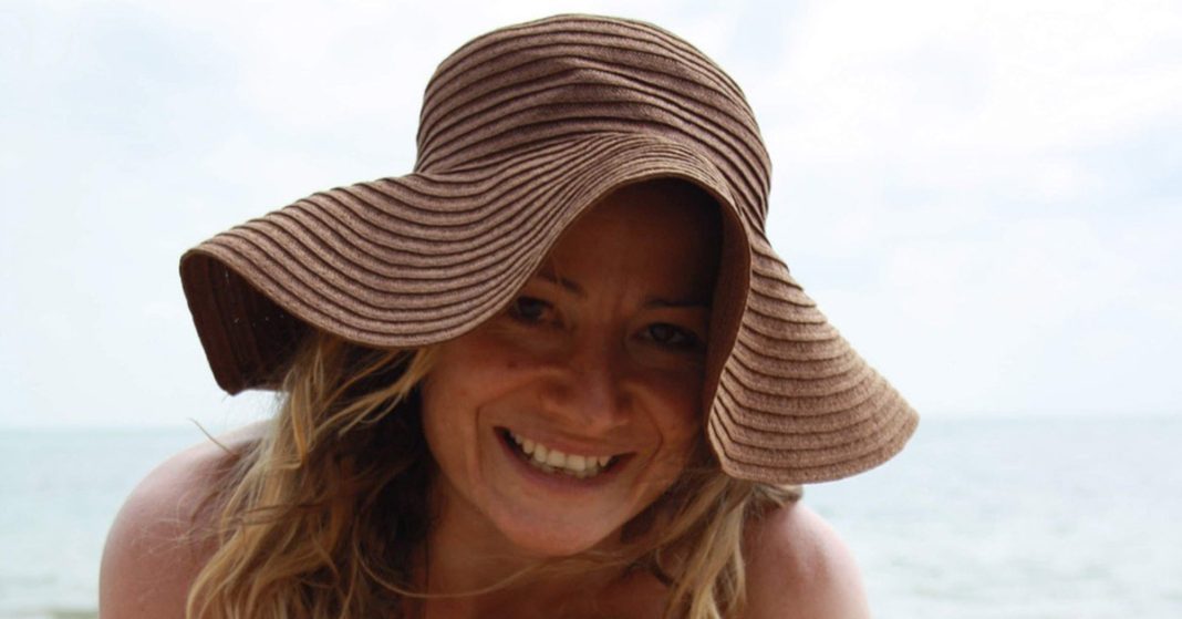 Woman with floppy straw hat smiling into the camera