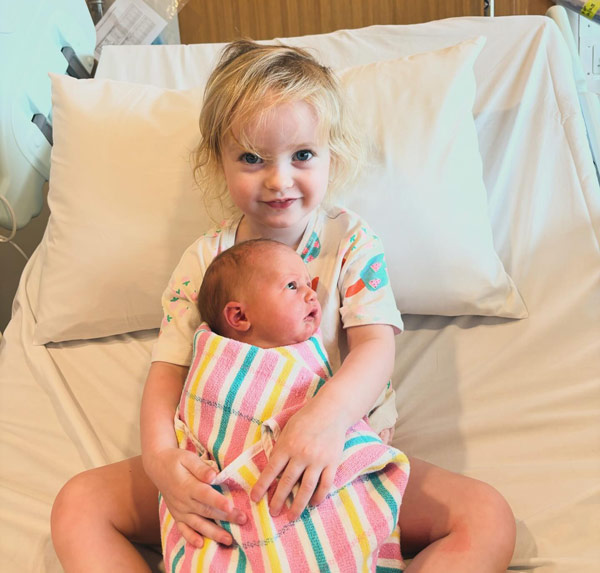 baby and small child sitting on a bed