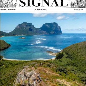 The front page of the Lord Howe island Signal with an idyllic coastal scene showcasing a broad view of a blue lagoon with coral patches, surrounded by a sandy shore, lush green hills, and two towering, rugged mountain peaks under a clear blue sky.