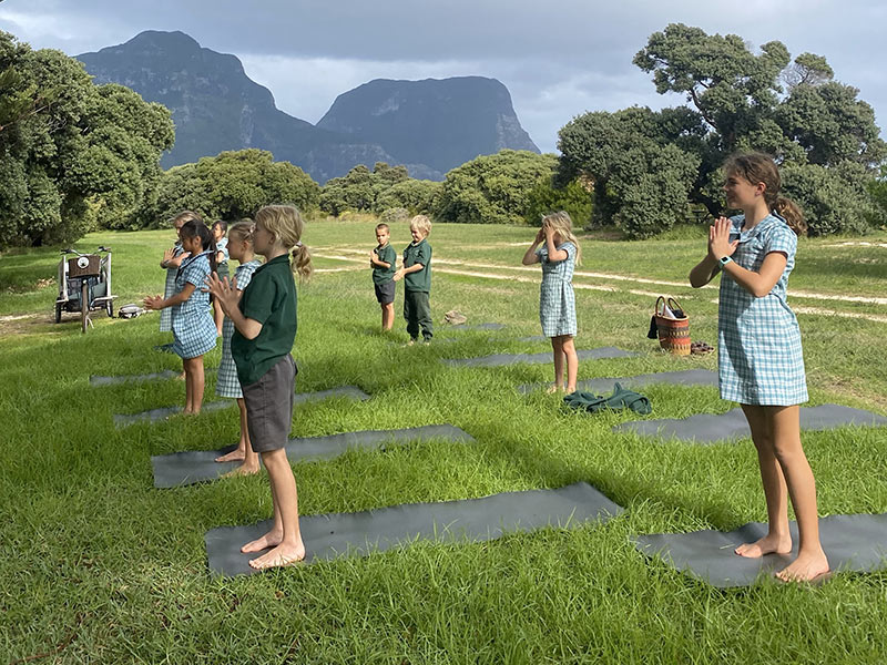 A photo of Lord Howe Island Central School students taking part in a yoga class outside.