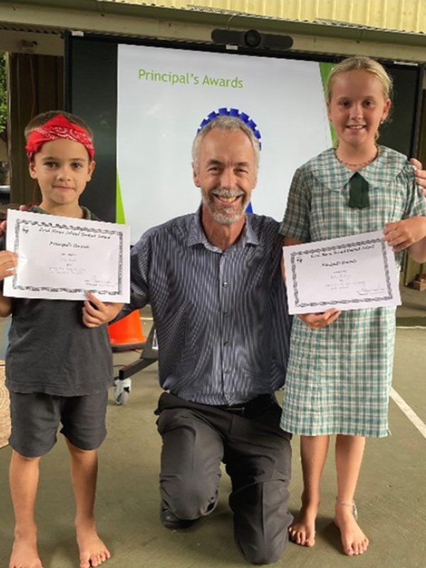 The Lord Howe Island Central School principal is awarding certificates to two students.