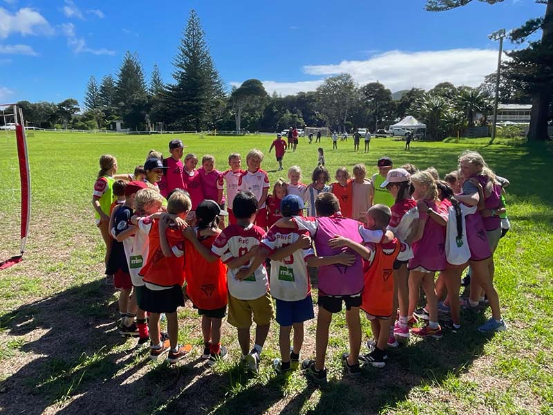 A group photo of children huddled in a circle at the recent Lord Howe Island Soccer camp.