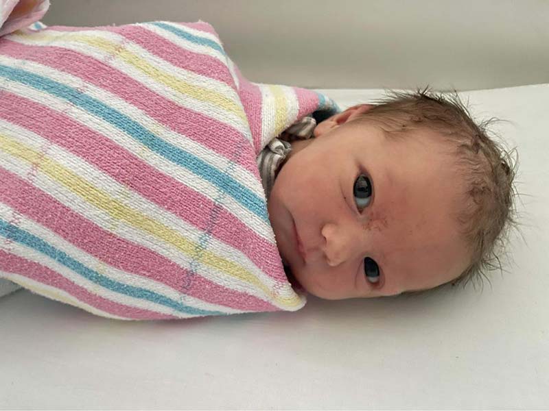 A photo of baby Birdie Joy Tierney wrapped up in a pink striped blanket. 