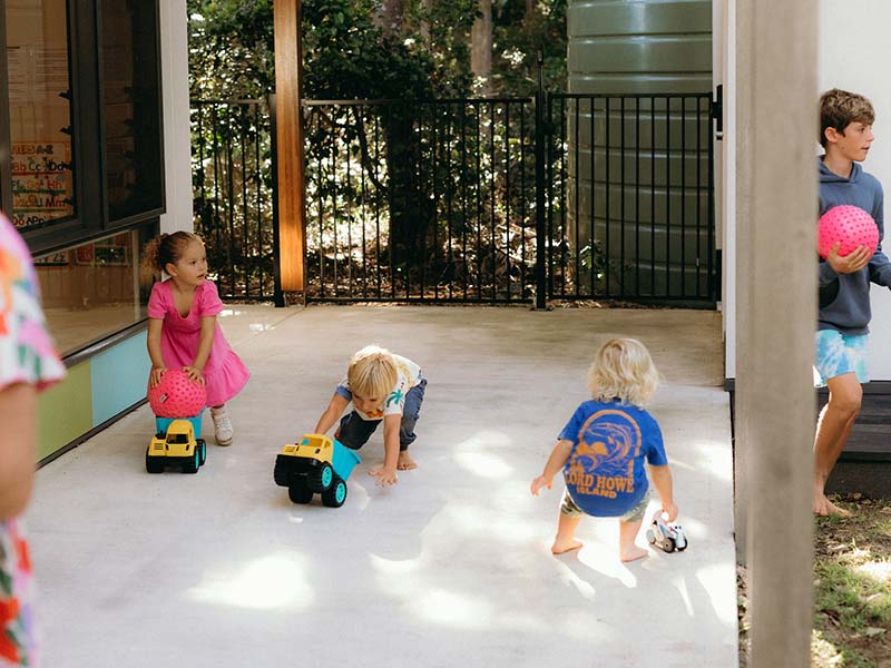 The opening of the new Lord Howe Island Preschool, children are out playing on the verandah with trucks and balls.