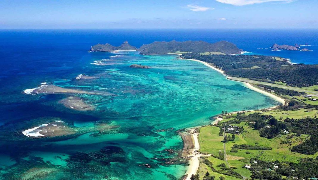 A tropical seascape and landscape with clear turquoise waters and green land.