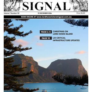 The front page of the Lord Howe Island Signal with an idyllic coastal scene showcasing a broad view of a blue lagoon with coral patches, surrounded by a sandy shore, lush green hills, and two towering, rugged mountain peaks under a clear blue sky.